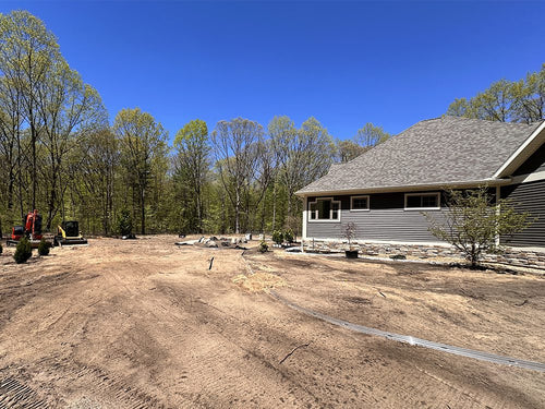 House under construction with a clear blue sky, no grass, and trees in the background