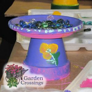 pink and blue dish with small stones in it on a small blue pedastal with a yellow flower painted on it