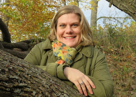 Photo of a blonde woman wearing a green jacket in a woodland setting