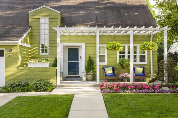 Light green house with a row of pink flower in front of it