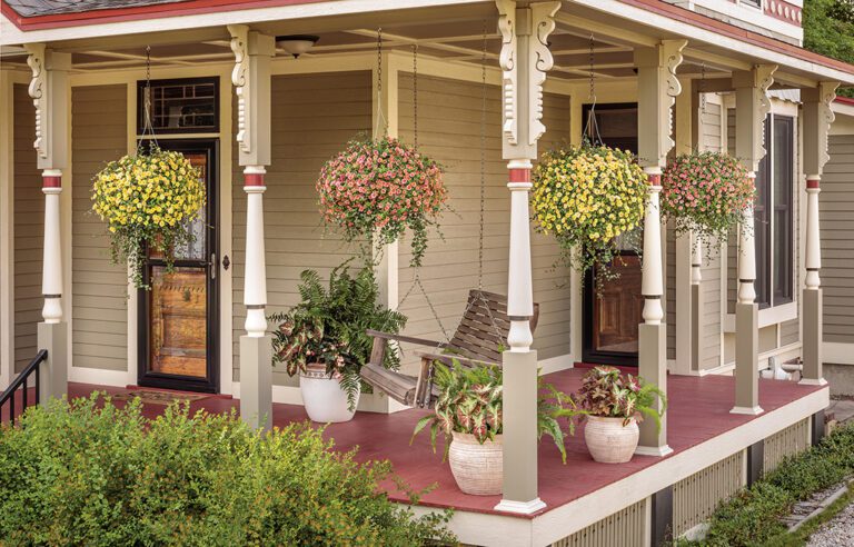 Front porch with numerous container planters and a swing chair