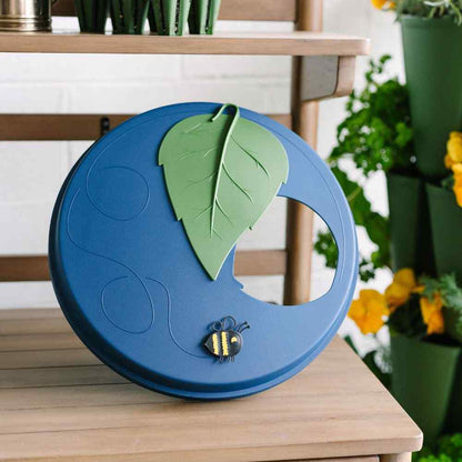 Blue lid with green leaf and bee design on a wooden surface - 